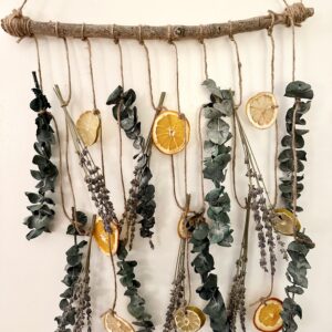 citrus slices, lavender, and eucalyptus hanging on jute twine string from a rustic wood branch