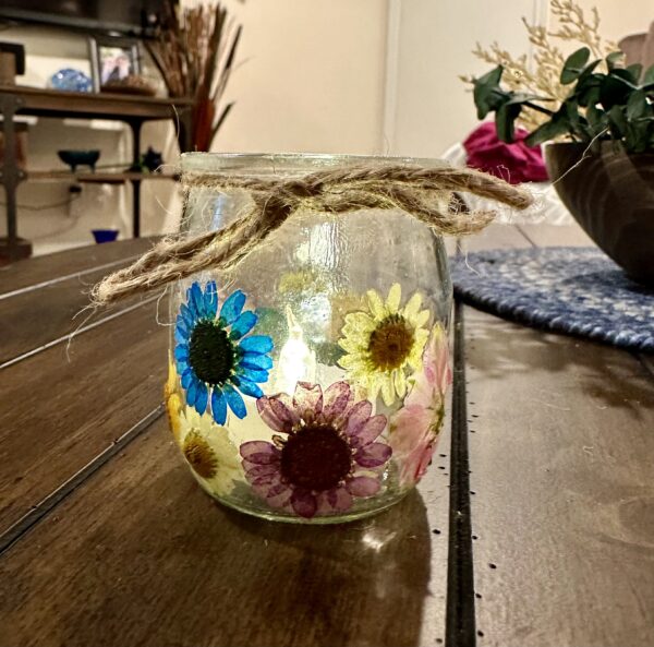 glass jar covered with dried pressed flowers on a rustic wood table