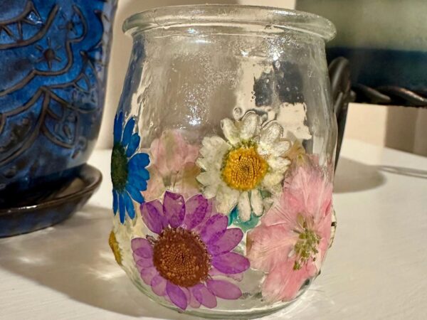 pressed flower candle jar on a white table