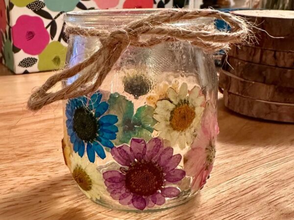 pressed flower candle jar on a wood table