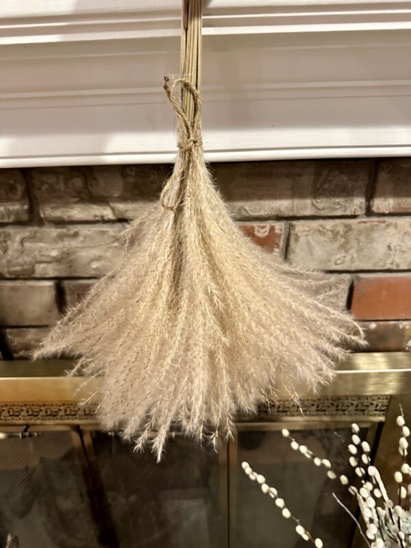 dried pampas grass stems hanging upside down from a brick fireplace mantle