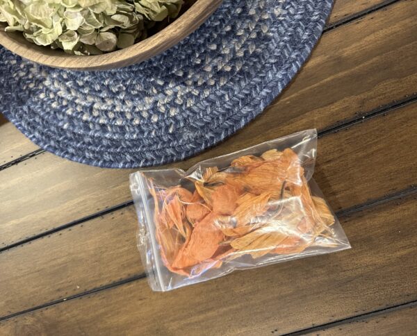 a clear pouch of orange lily dried flower petals on a rustic wood table