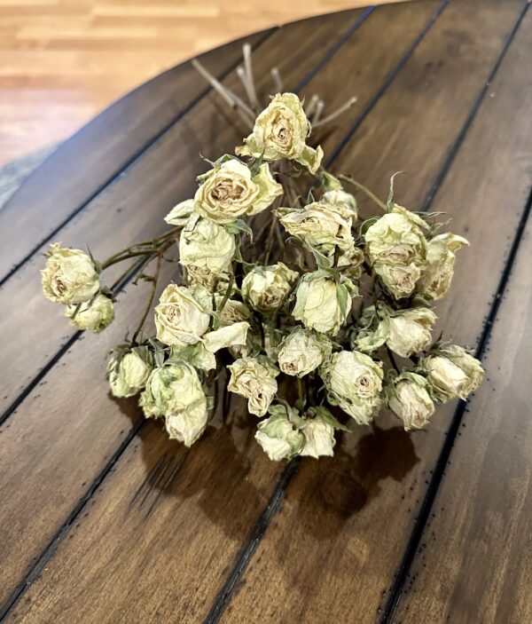 mini white dried roses on a rustic wood table